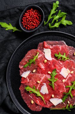 Arugula ve parmesan peynirli mermer sığır carpaccio. Siyah arka plan. Üst görünüm.