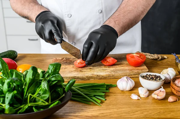 Chef Luvas Pretas Está Cortando Tomates Uma Tábua Corte Madeira — Fotografia de Stock