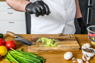 Siyah eldivenli bir şef taze Avacado Hass 'tan guacamole hazırlıyor..