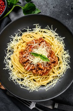 Domatesli spagetti bolonez makarna ve kıyma, parmesan peyniri ve fesleğen. Siyah arka plan. Üst görünüm.