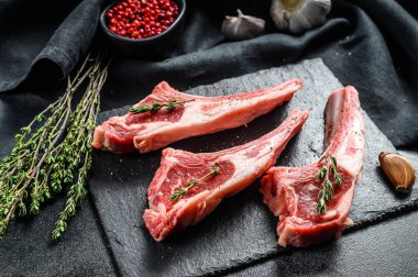 Çiğ kuzu pirzolası, biberiye ve baharatlı kuzu pirzolası. Organik biftek. Siyah arka plan. Üst görünüm.