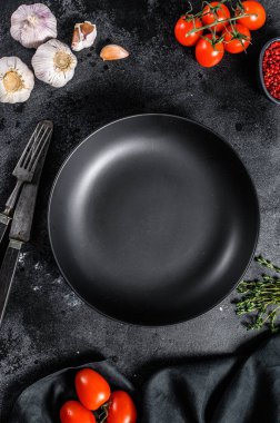 Taze çiğ sebze ve sebzelerin ortasında siyah tabak. Sağlıklı, temiz yemek, vejetaryen, diyet yemek konsepti. Siyah arka plan. Üst Manzara. Boşluğu kopyala.