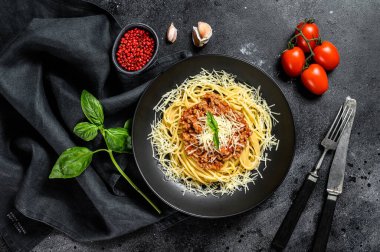 Domatesli spagetti bolonez makarna ve kıyma, parmesan peyniri ve fesleğen. Siyah arka plan. Üst görünüm.