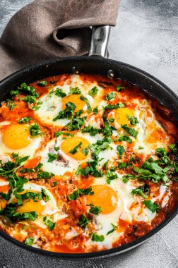 Kızarmış yumurta ve domateslerle kahvaltı. Shakshuka tavada. Geleneksel Türk yemekleri. Gri arka plan. Üst görünüm.