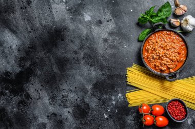 İtalyan spagetti bolonezi için yemek malzemeleri. Çiğ makarna, fesleğen, kıyma, domates. Siyah arka plan. Üst Manzara. Boşluğu kopyala