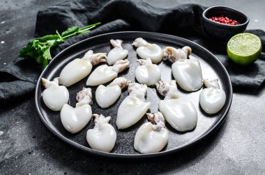 Biberiye ve maydanozlu taze mürekkep balığı. Siyah arka plan. Üst görünüm.