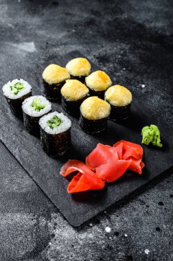 Siyah taşla servis edilen çeşitli suşiler. Siyah arka plan. Üst görünüm.
