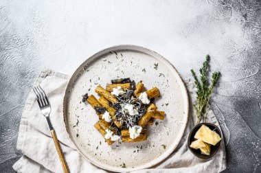 Siyah mantarlı makarna, beyaz mantar, krema sosu ve ricotta peyniri. Gri arka plan. Üst Manzara. Metin için boşluk.