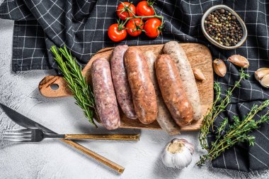 Kekik, sarımsak ve biberle çeşitli taze sosisler. Gri arka plan. Üst görünüm.