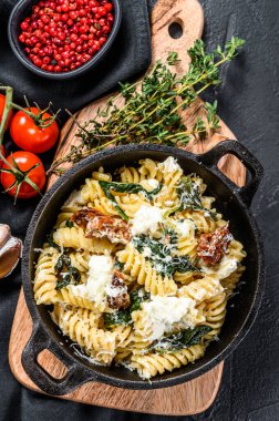 Ispanaklı Fusilli makarna, kurutulmuş domates ve tavada ricotta peyniri. Siyah arka plan. Üst görünüm.