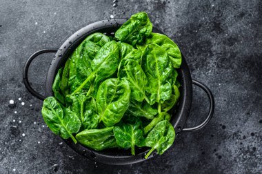 Kevgir gibi taze ıspanak. Siyah arka plan. Üst görünüm.