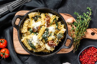 Kremalı ıspanak soslu ve kurutulmuş domatesli lezzetli makarna fusili. Siyah arka plan. Üst görünüm.