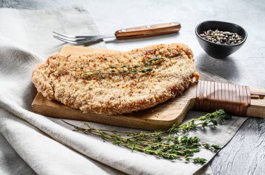 Ekmek kırıntıları içinde çiğ tavuk şnitzel. Gri arka plan. Üst görünüm.