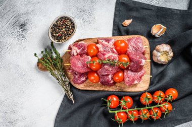Kesme tahtasında çiğ et kebabı. Domates ve baharatlı barbekü. Gri arka plan. Üst görünüm.