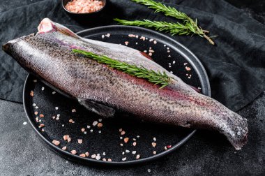 Kafasız, tuzsuz ve biberiyeli çiğ alabalık. Siyah arka plan. Üst görünüm.