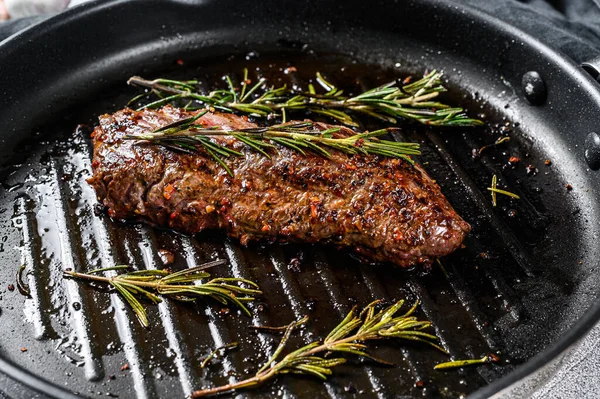 Cooked top blade, Denver steak in a pan. Marble meat beef. Gray background. Top view.