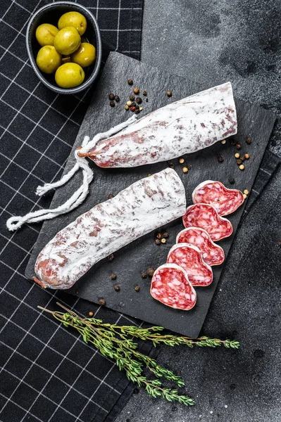 Fuet Salam dilimleri ve Rosemary. Geleneksel İspanyol sosisi. Siyah arka plan. Üst görünüm.