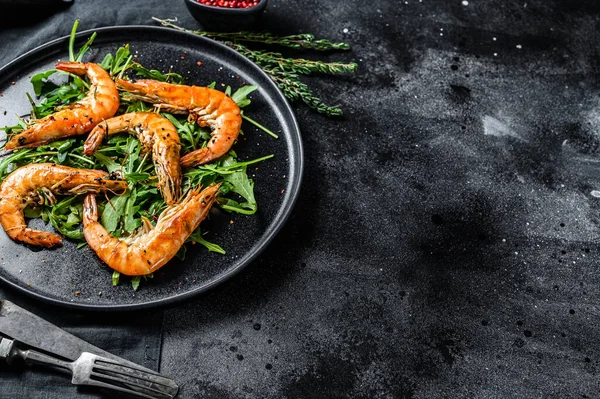 Grilled giant prawns, shrimps, arugula and spices. Black background. Top view. Copy space.