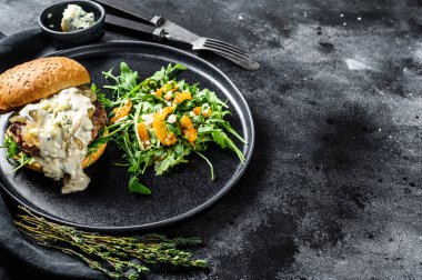 Ev yapımı peynirli çizburger, domuz pastırması, mermer sığır eti ve soğan reçeli roka ve portakallı salata. Siyah arka plan. Üst Manzara. Boşluğu kopyala.