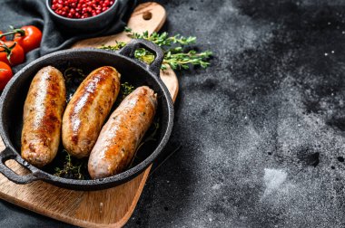 Dökme demir tavada domuz sosisi. Siyah arka plan. Üst Manzara. Boşluğu kopyala.