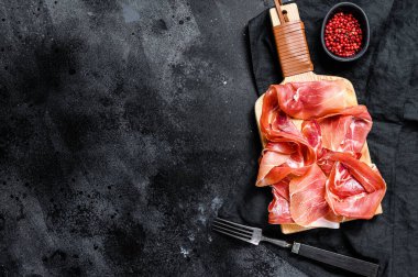 İspanyol jamonu Serrano, jambon. Siyah arkaplan, üst görünüm, metin için boşluk.