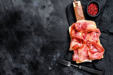 Spanish jamon Serrano, ham. Black background, top view, space for text. clipart
