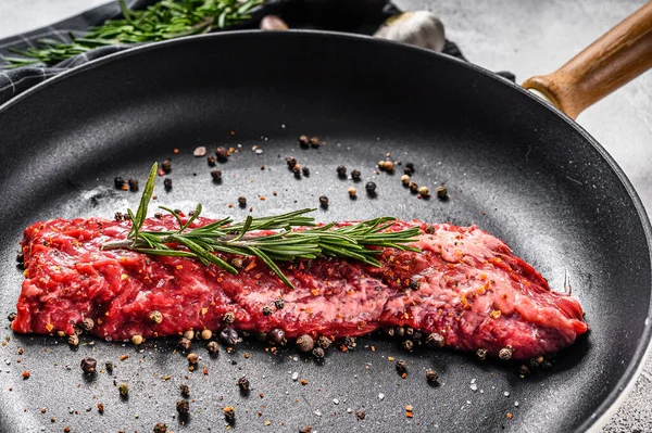 Raw strip vegas steak in a pan with cooking ingredients. Gray background. Top view.