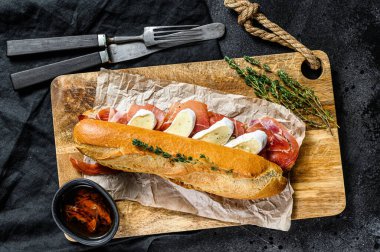 Jambonlu sandviç, dilimleme tahtasındaki peynirli peynirli sandviç. Siyah arkaplan, üst görünüm