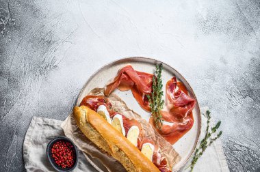 Jamon jambonlu sandviç, paleta iberica, kesim tahtasında Camembert peyniri. Gri arkaplan, üst görünüm, metin için boşluk.