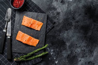 Taş bir tahtada alabalık bifteği filetosu. Siyah arka plan. Üst Manzara. Boşluğu kopyala.