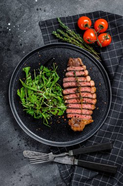 Dilimlenmiş sığır filetosu, roka ile mermer et. Siyah arka plan. Üst görünüm.