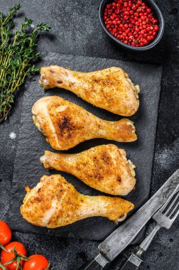 Fırında tavuk budu, otlu bacaklar. Siyah arka plan. Üst görünüm.