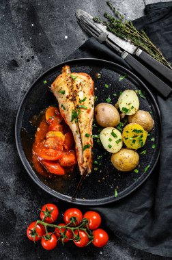 Fırında patatesle domates balığı pişirmek. Taze deniz ürünleri. Siyah arka plan. Üst görünüm.