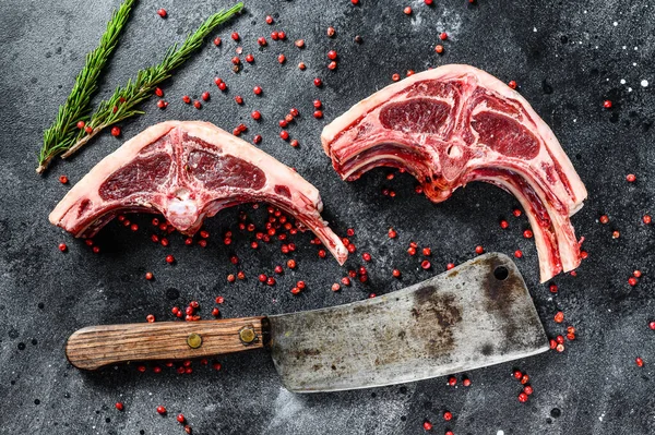raw lamb chops fresh cut with meat cleaver. Black background. Top view.