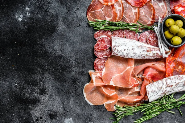 Geleneksel İspanyol mezelerinden yapılmış bir tabak et. Chorizo, Jamon Serrano, Lomo ve Fuet. Siyah arka plan. Üst Manzara. Boşluğu kopyala.