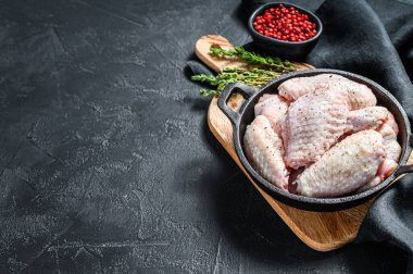 Tavada baharat ve bitkilerle çiğ tavuk kanadı. Siyah arka plan. Üst Manzara. Boşluğu kopyala.