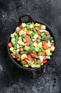 Donmuş sebzeler. Brokoli, kiraz domatesleri, mısır, bezelye, havuç. Siyah arka plan. Üst görünüm.