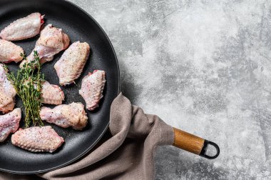 Baharatlı tavuk kanatları ve tavada pişmeye hazır bitkiler. Gri arka plan. Üst Manzara. Boşluğu kopyala.