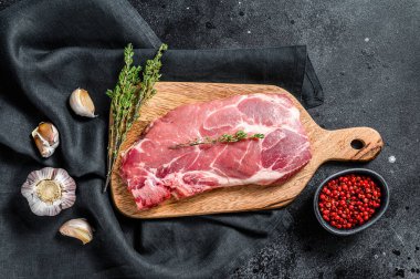 Tahta bir tahtanın üzerinde çiğ mermer domuz bifteği. Organik et. Siyah arka plan. Üst görünüm.