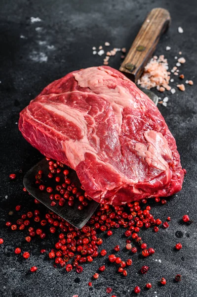 Raw Chuck eye roll steak on meat cleaver. Organic beef. Black background. Top view.