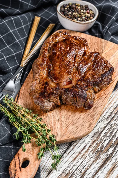 Cooked grilled Chuck eye roll steak on a chopping Board. White background. Top view.