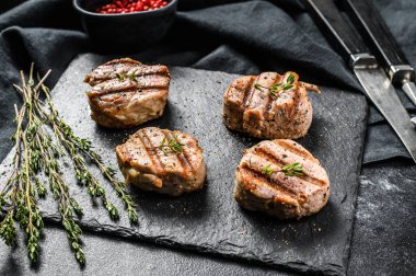 Yumuşak kemiksiz ızgara domuz pirzolası. Biftek filetosu. Siyah arka plan. Üst görünüm.