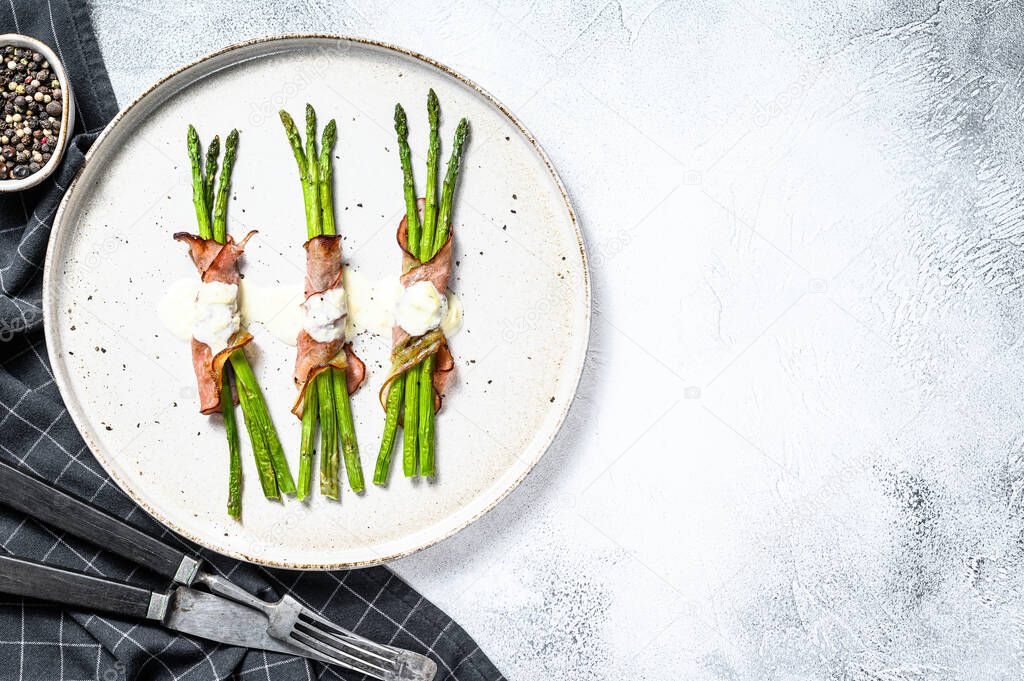 Grilled organic asparagus wrapped in pork bacon. Gray background. Top view. Copy space.