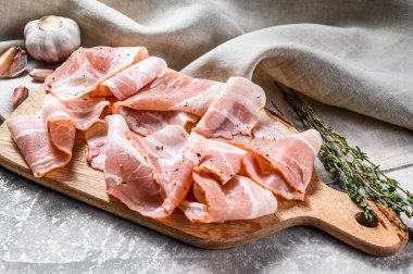 Biberli pastırma ve kekik dilimleme tahtasında. Organik çiğ domuz eti. Gri arka plan. Üst görünüm.