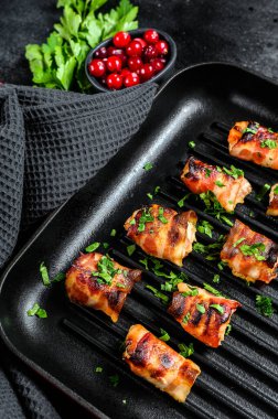 Tavaya sarılmış pastırmalı tavuk göğsü. Siyah arka plan. Üst görünüm.