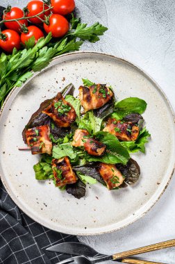 Domuz pastırmasına sarılı fırında tavuk göğsü ile yeşil salata. Gri arka plan. Üst görünüm.