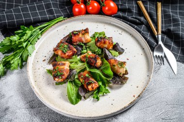 Domuz pastırmasına sarılı fırında tavuk göğsü ile yeşil salata. Gri arka plan. Üst görünüm.