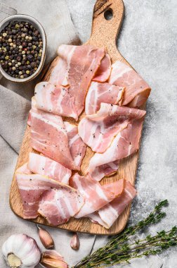 Biberli pastırma ve kekik dilimleme tahtasında. Organik çiğ domuz eti. Gri arka plan. Üst görünüm.