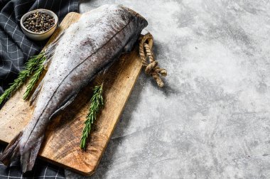 Kesme tahtasındaki çiğ mezgit balığı. Gri arka plan. Üst Manzara. Boşluğu kopyala.