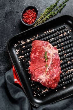 Izgara tavada üst bıçak bifteği, çiğ et, mermer sığır eti. Siyah arka plan. Üst görünüm.